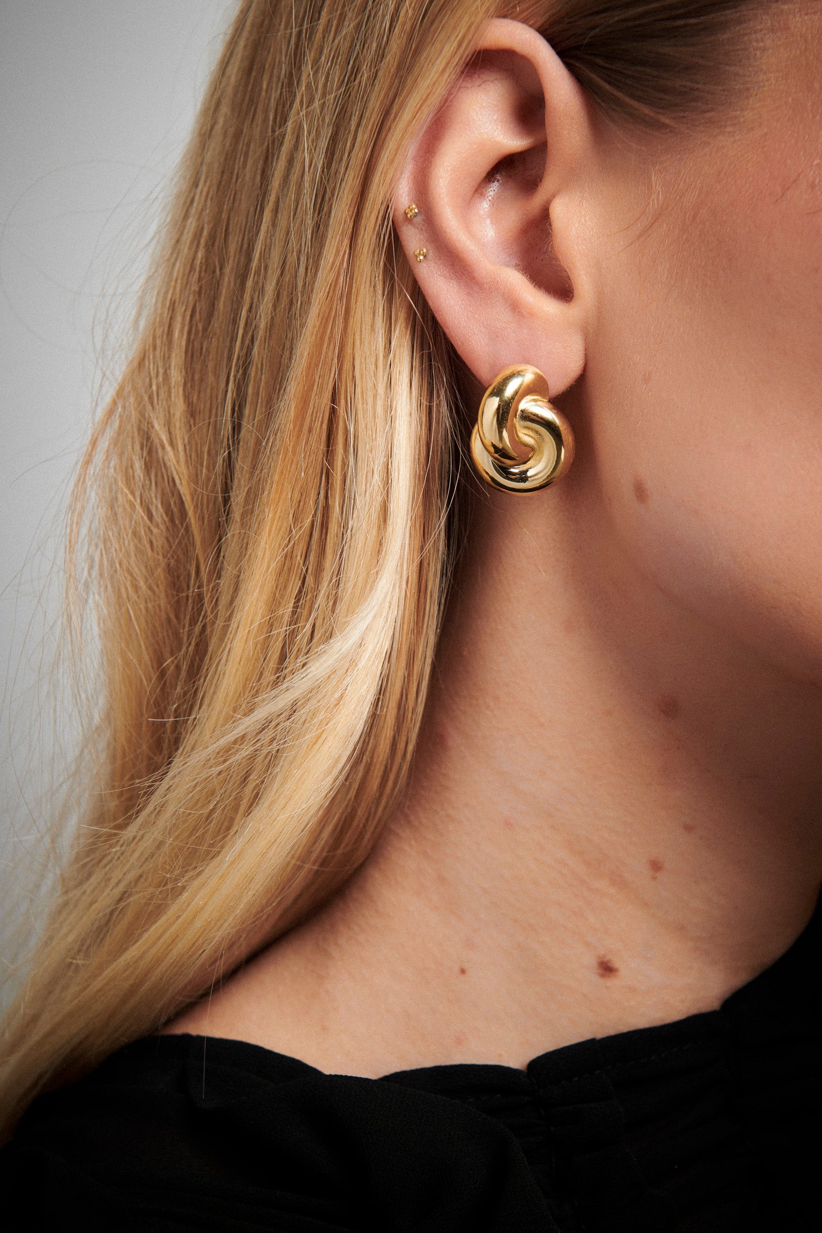 Mini Double Knot Earrings in gold, featuring interlocking loops for a sculptural, polished look.