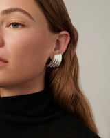 Double-hoop earrings with a sculptural silhouette, crafted in brass with 14k gold vermeil or 925 sterling silver vermeil—lightweight and bold.
